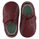 A pair of childrens adjustable strap shoes, viewed from the top. They are facing in opposite directions. They are in wine red leather with a large adjustable strap over the top of the foot. They have a  pale blue leather lining and insole. The sole is a natural gum colour.