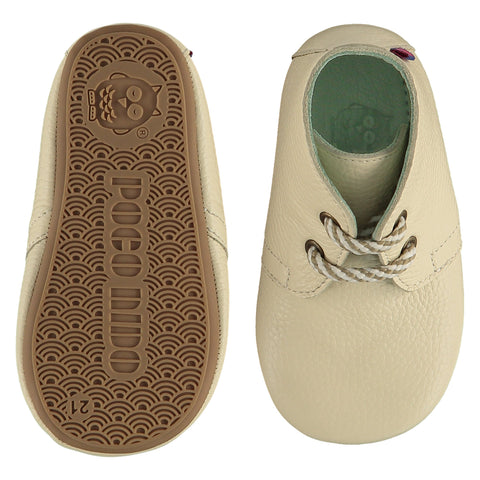 A pair of childrens lace up desert boots, one viewed from the top, one is a view of the sole. They are in chalk colour leather with striped laces. They have a  pale blue leather lining and insole. The sole is a natural gum colour.