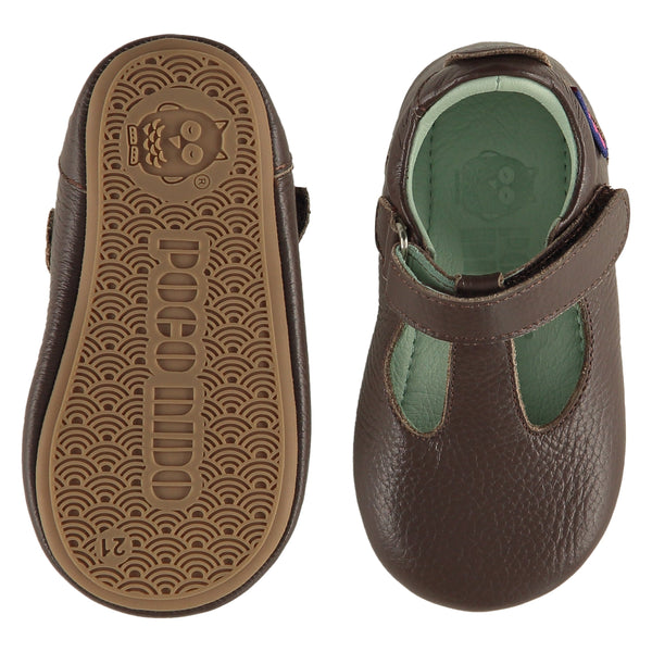 A pair of childrens T bar shoes, one viewed from the top, one is a view of the sole. They are in dark brown leather. They have a pale blue leather lining and insole and an adjustable strap. The sole is a natural gum colour.