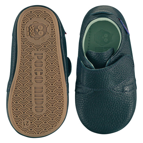 A pair of childrens adjustable strap shoes, one viewed from the top, one is a view of the sole. They are in dark teal colour leather with a large adjustable strap over the top of the foot. They have a  pale blue leather lining and insole. The sole is a natural gum colour.