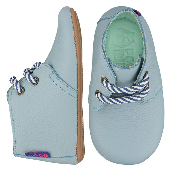 Mighty Shoes Blue Desert Boot. Children's ankle boot in sky blue colour leather. Barefoot ankle boot with blue and white stripe laces and a flat, super flexible TPU rubber sole. The sole has the Poco Nido logo on it. View of top and side. Poco Nido baby shoes make unique gifts - as christmas gifts, stocking fillers, baby shower gifts, new parent gifts, to celebrate new walking skills and many other occasions. They are great toddler shoes too and are perfect for daycare settings. 
